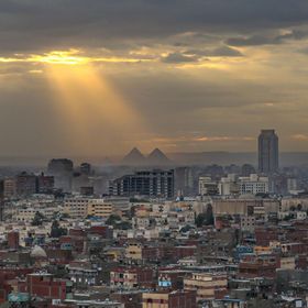 صورة تظهر مباني سكنية وتجارية في مدينة القاهرة، وفي الخلفية أهرامات الجيزة، مصر - المصدر: بلومبرغ